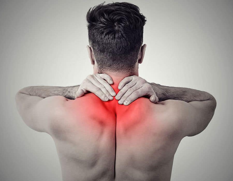 A person, viewed from behind, holds their neck with both hands. The neck and upper back are highlighted in red, indicating pain, against a neutral grey background.